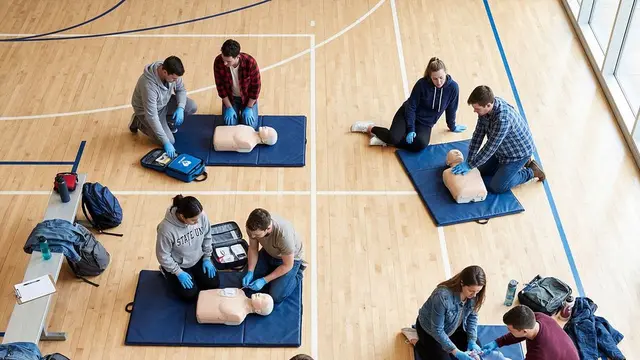 Pairs practising CPR together on a training floor